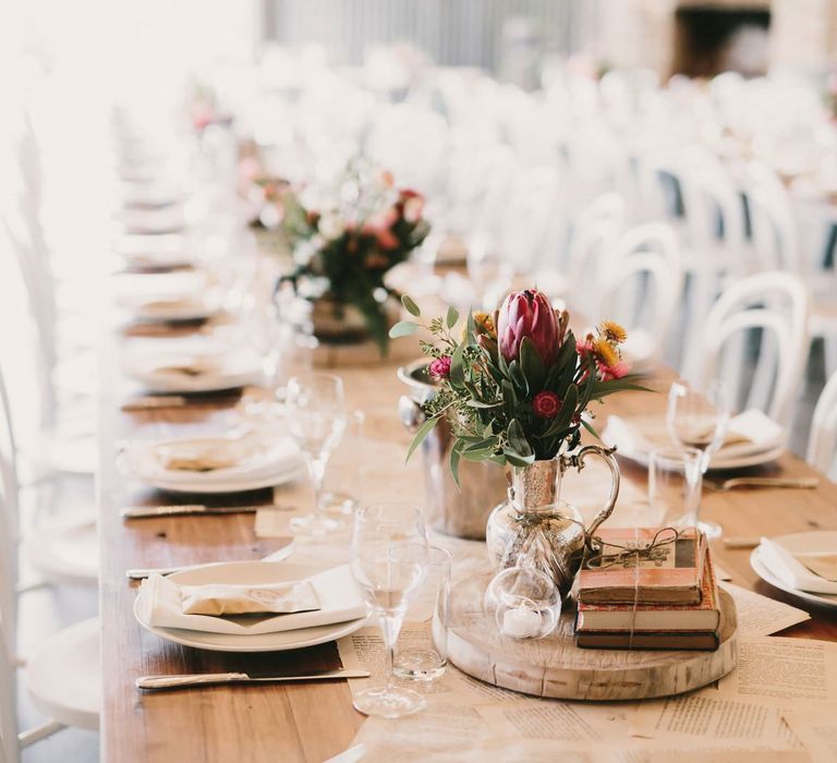 Old Book Pages Table Runner with Tree Slices, Stacked Books and Flowers in Jars as Centrepieces