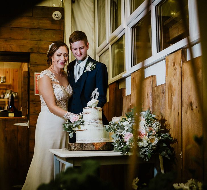 Cutting the Semi Naked Wedding Cake | Bride in Lace Long Sleeve Martina Liana Wedding Dress | Groom in Navy Three-piece Suit | Lusty Glaze Beach Wedding Newquay Cornwall | Alexa Poppe PhotographyLusty Glaze Beach Wedding Newquay Cornwall | Alexa Poppe Photography