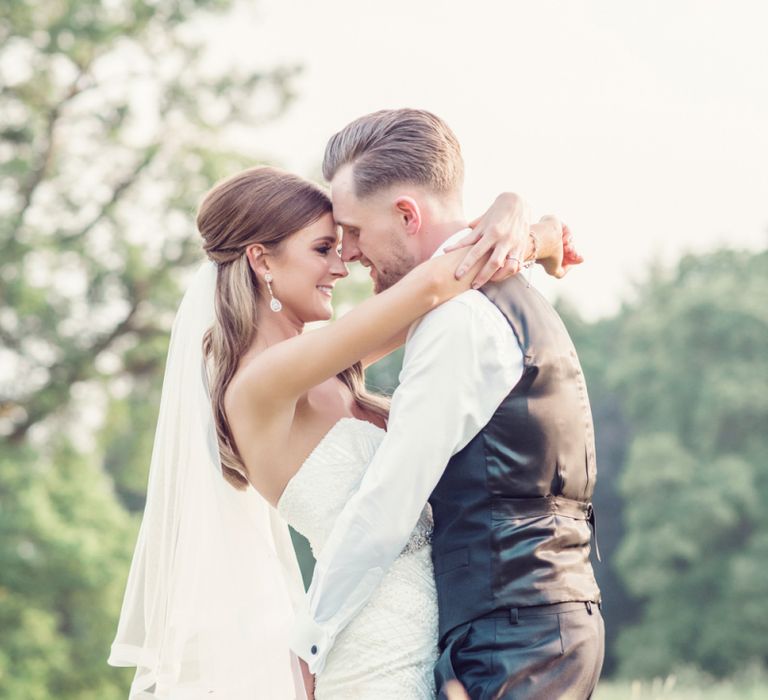 Bride in Beaded Fishtail Wedding Dress and Groom in Gieves &amp; Hawkes Tuxedo Cuddling