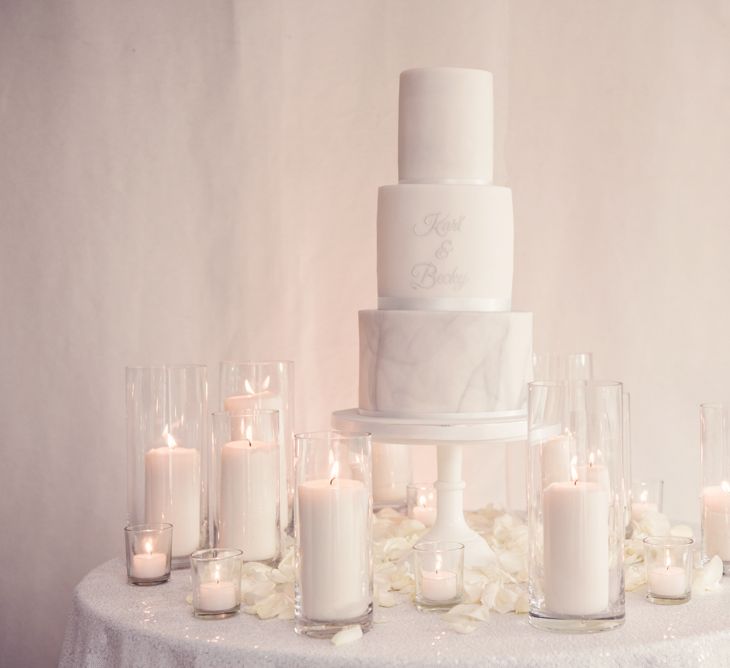 Three Tier Wedding Cake with Marble Tier and Motif Surrounded by White Candles and Petals