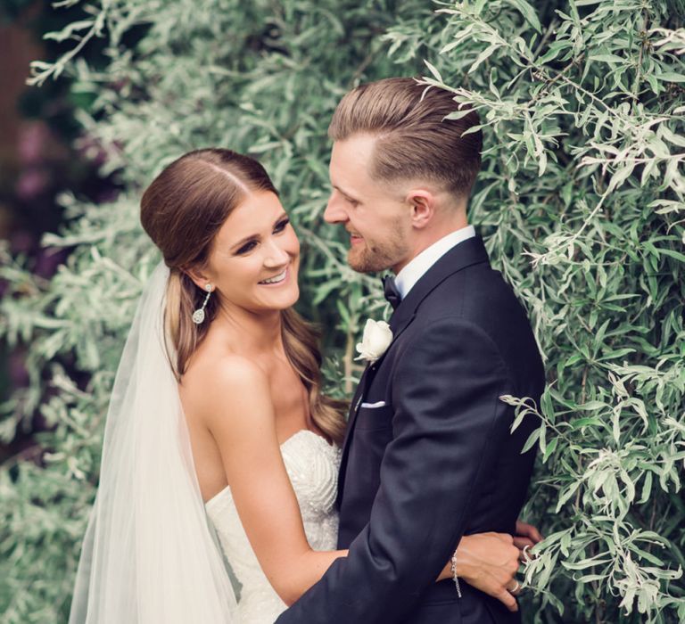 Bride in Beaded Fishtail Wedding Dress and Groom in Gieves &amp; Hawkes Tuxedo Embracing