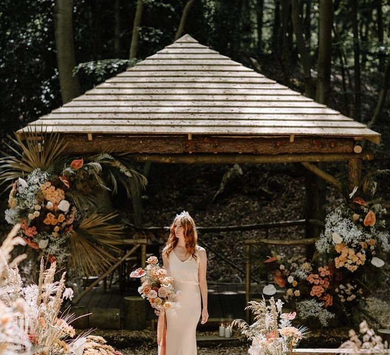 Bride in Fitted Weddng Dress at Woodland Wedding Ceremony Decorated in Orange and Dried Flower Arrangements