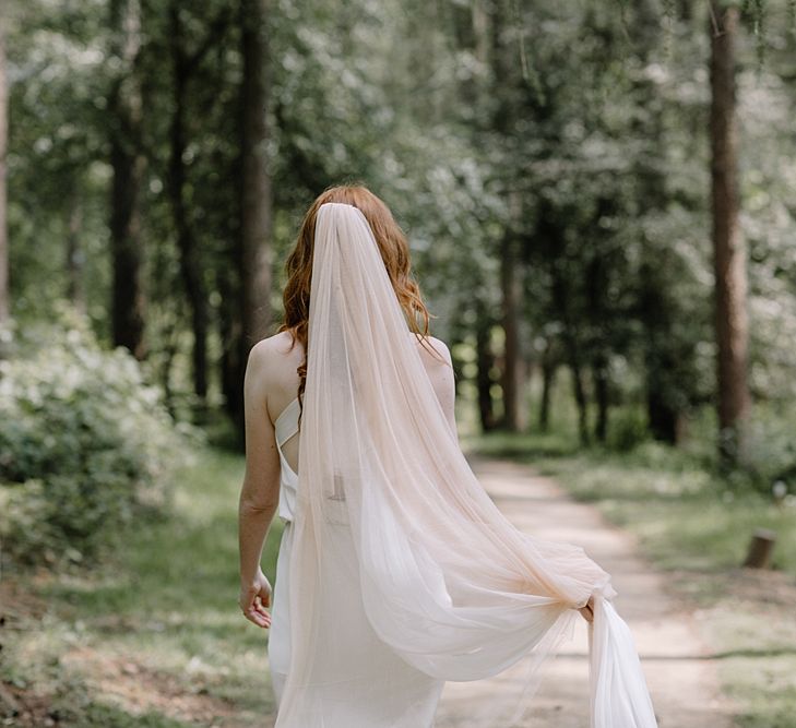 Bride Walking in the Woodland with Blush Wedding Veil