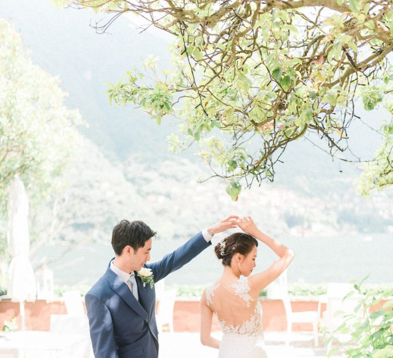 Groom in Navy Suit Twirling his Bride in Fitted Anna Kara Wedding Dress