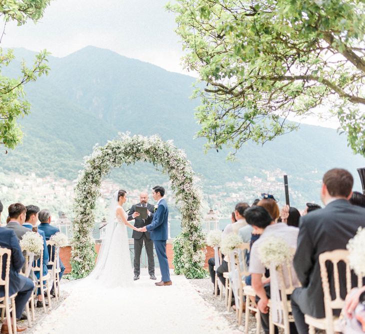 Outdoor Wedding Ceremony with Bride and Groom Saying their Vows in Front of a Gypsophila Floral Arch