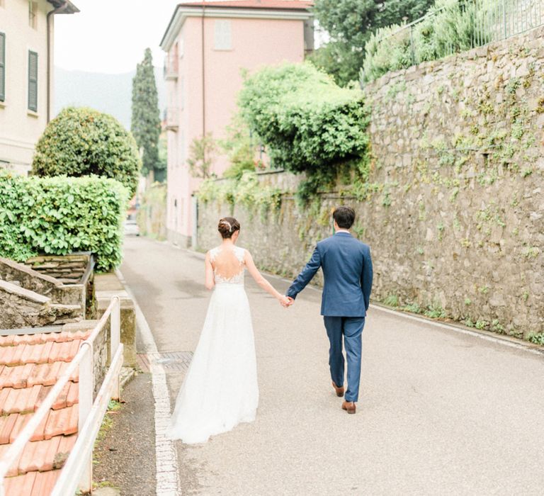 Bride in Anna Kara Wedding Dress and Groom in Three-piece Navy Wedding Suit Holding Hands