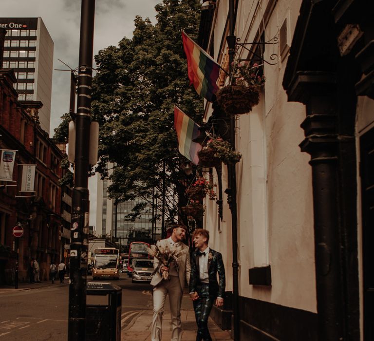 Stylish groom in a patterned and beige suit walking through Manchester Gay Village