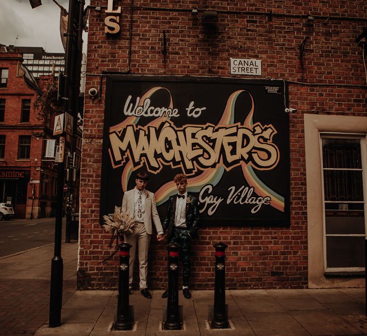 Gay couple standing in front of wall art in Manchester's Gay Village