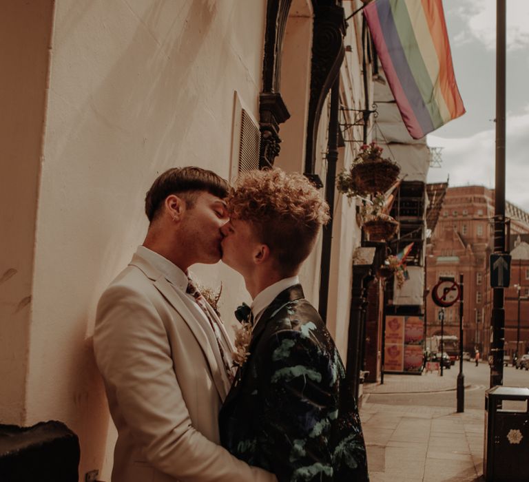 Same sex couple kissing under a gay pride flag