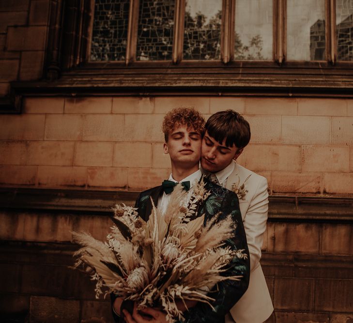 Groom in beige suit embracing his husband at a Manchester elopement