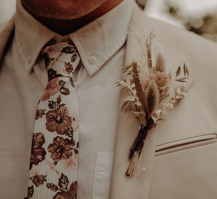 Patterned tie, beige suit and dried flower buttonhole