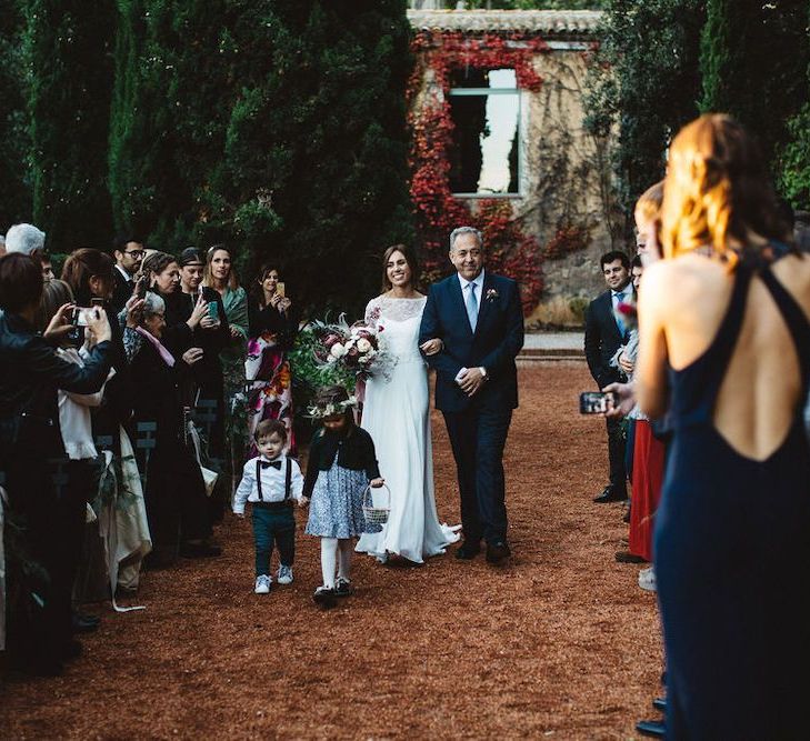 Bride Walking Down the Aisle in a Jordi Anguera Wedding Dress with Lace Overlay