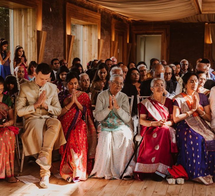 Wedding guests praying at Elmore Court Hindu wedding ceremony