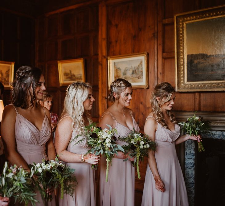 Bridesmaids in blush pink dresses with green bouquets