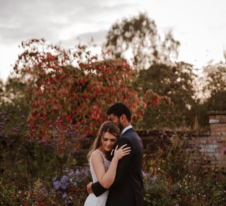 Groom embracing his bride in Elmore Court gardens