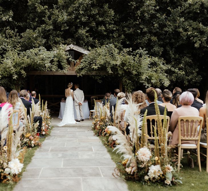 Outdoor wedding ceremony at Bury Court Barns with bride in Rime Arodaky dress