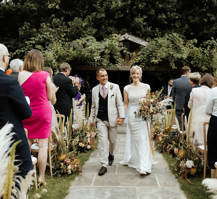 Bride and groom walking up the aisle as husband and wife with bride in Rime Arodaky gown