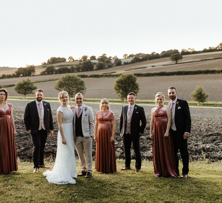 Wedding party portrait with the bride in a Rime Arodaky gown, bridesmaids in pink velvet dresses and groomsmen in  black and stone suits