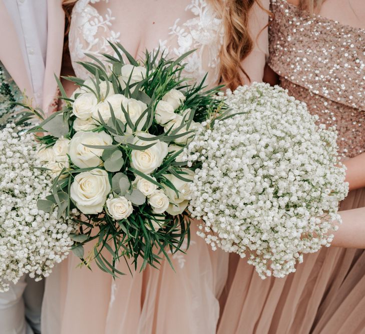 White Wedding Flowers Against Pink Wedding Dress and Bridesmaid Dresses