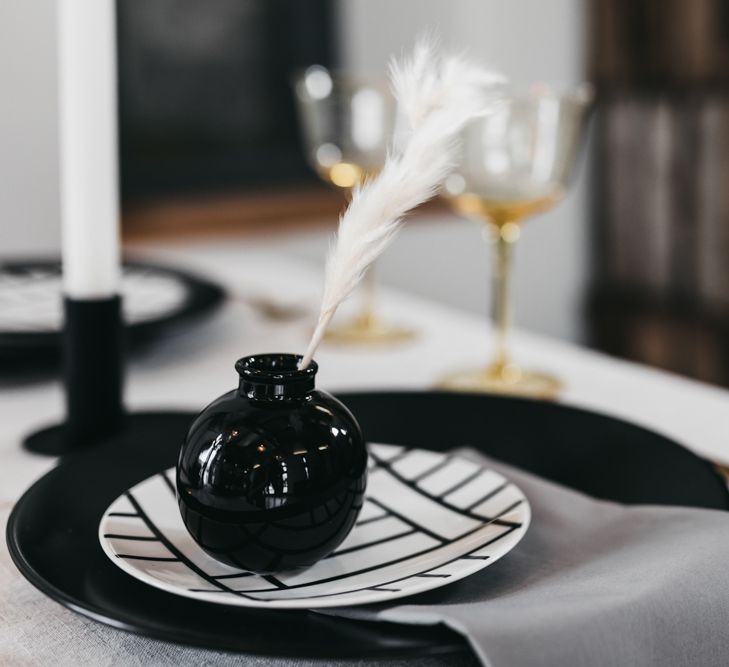 Place setting with monochrome tableware and white feather decor