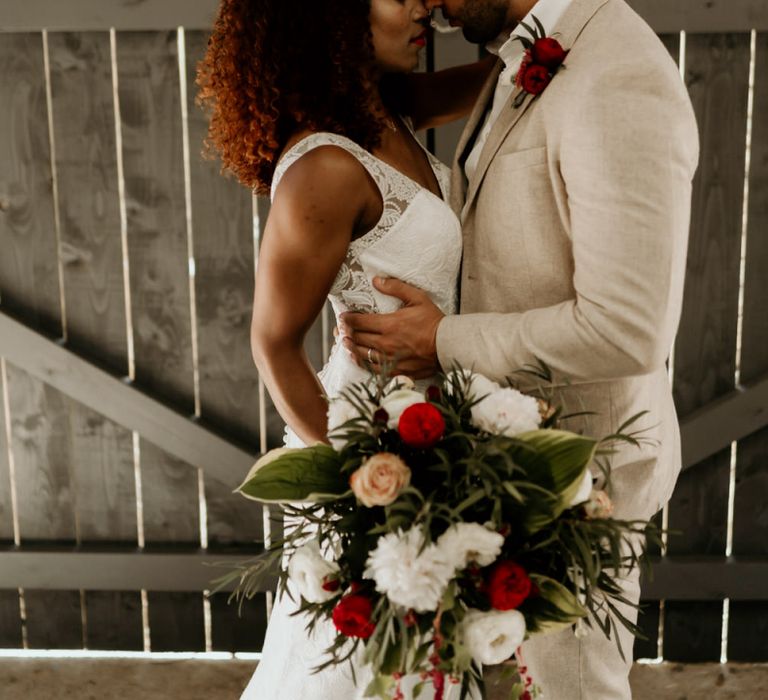 Black Bride with Afro Hair in a Lace Wedding Dress and Groom in Blazer Embracing Under a neon Wedding Sign