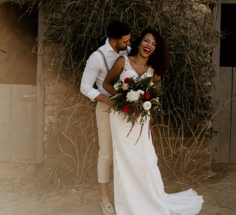 Black Bride with Afro Hair in a Lace Wedding Dress and Groom in White Shirt and Braces Laughing