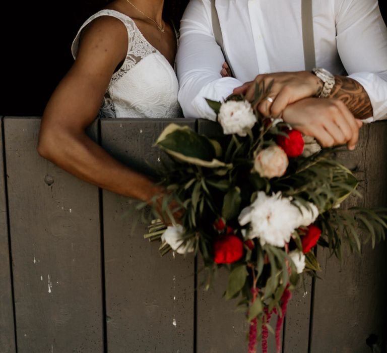 Black Groom in White Shirt and Braces Kissing Bride with Afro Hair in a Lace Wedding Dress