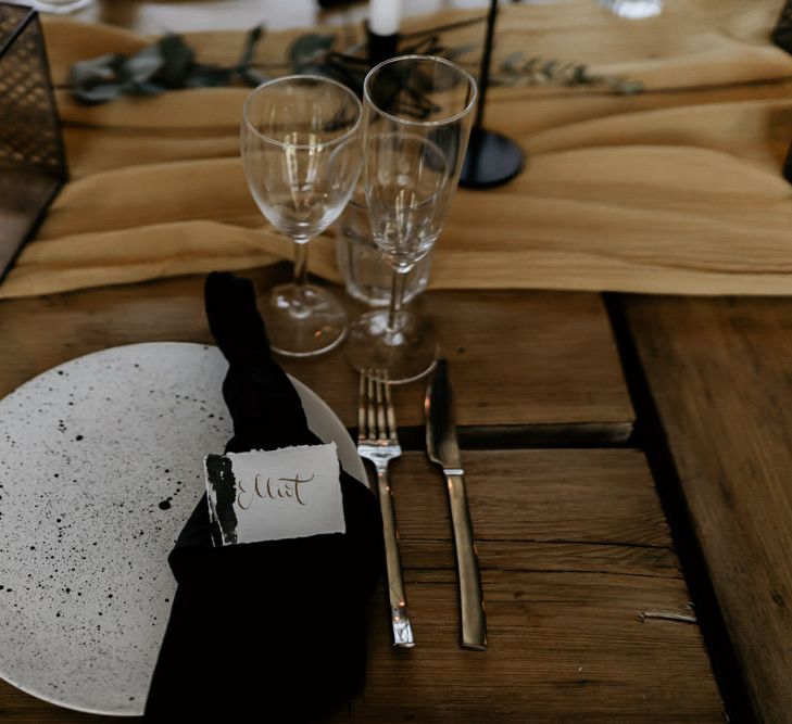 Elegant Place Setting with Speckled Tableware, Black Table Linen and Calligraphy Name Place Card