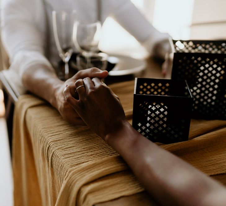 Black Bride and Groom Holding Hands Across The Table