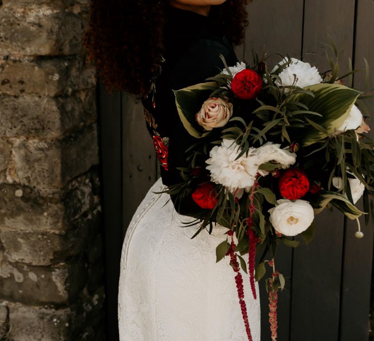 Black Bride with Afro Hair Wearing Leather Jacket Holding a Red, White and Foliage Bouquet