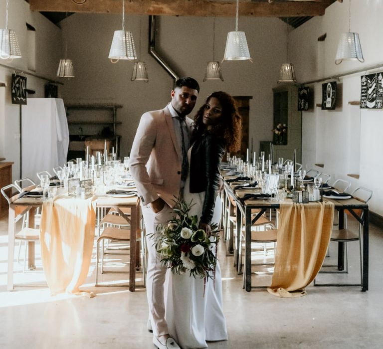 Black Bride in Lace Wedding Dress and Leather Jacket Standing Next to Groom in Blazer and Loafers