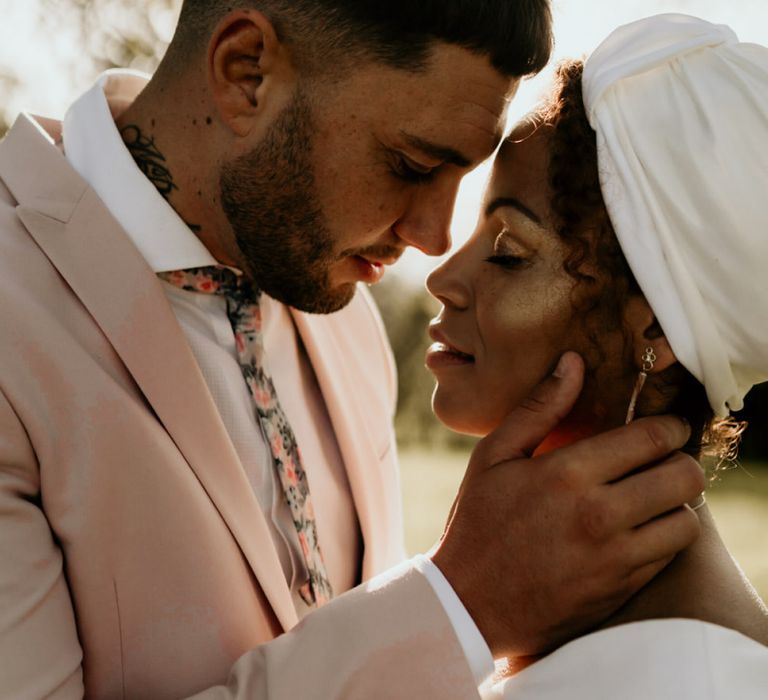 Black Bride with Head Wrap and Cheek highlighter and Groom in Pink Blazer Embracing