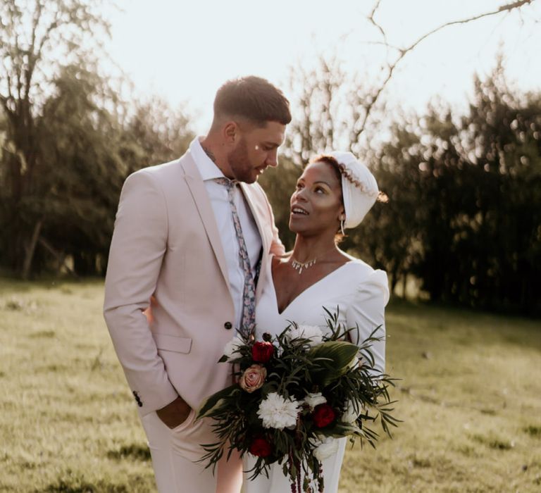 Black Bride in White Jumpsuit with Head Wrap  and Groom in Pink Suit