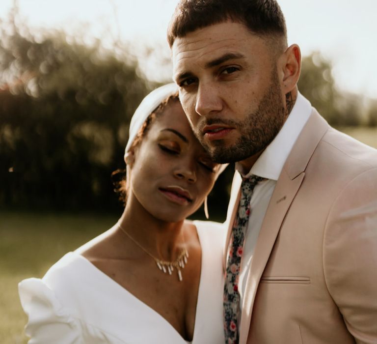 Black Bride in White Jumpsuit with Head Wrap  and Groom in Pink Blazer