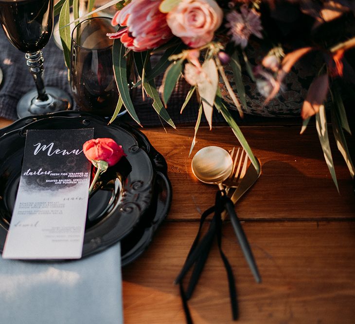 Place Setting with Black Tableware and Cutlery, Menu Card and Floral Centrepiece