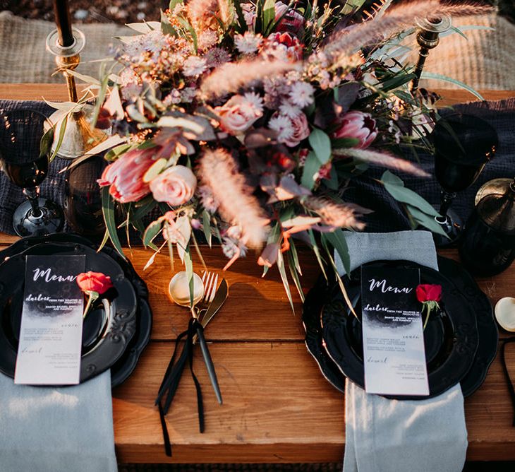 Table Place Settings with Black Tableware and Cutlery, Menu Cards and Deep Red Floral Centrepiece