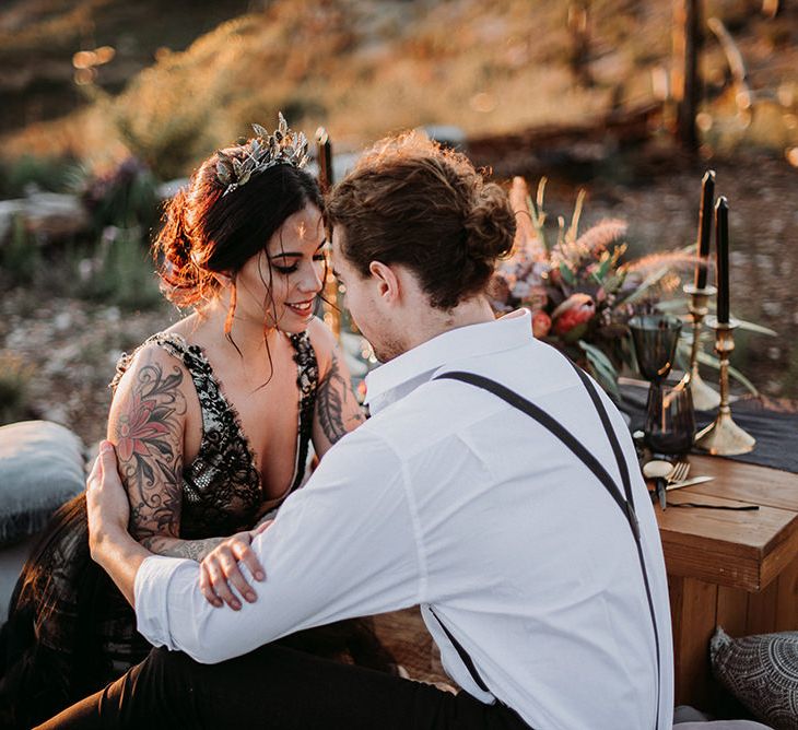 Bride in Black Wedding Dress and Gold Crown Headdress Embracing with Her Groom in White Shirt and Braces