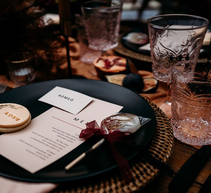 Place setting rattan mat, black plate, menu card and wedding favours