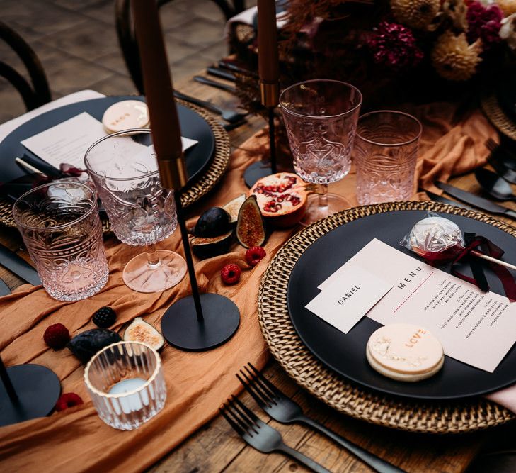 Place setting with black tableware and embroidered napkin