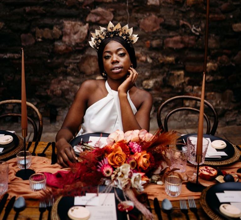 Bride sitting at a caramel, raspberry and rust wedding theme tablescape