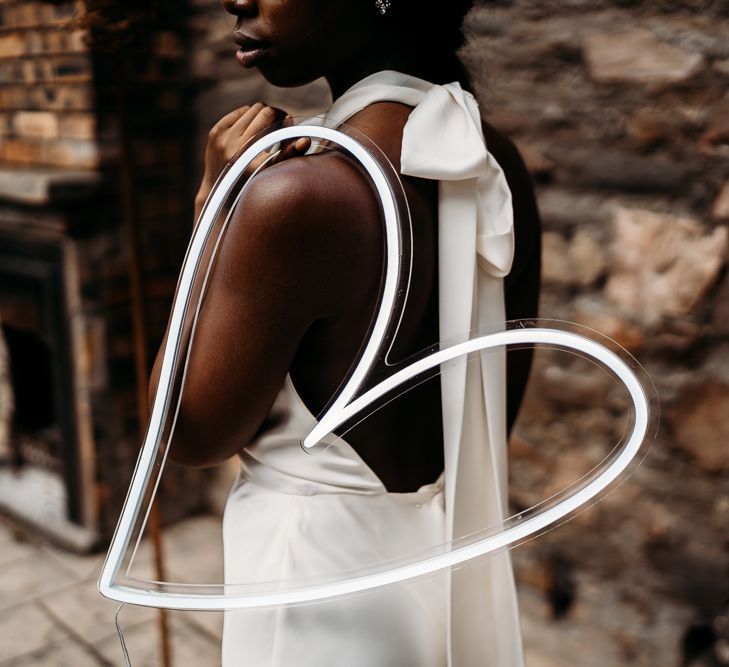 Bride holding a white neon heart on her arm for rust wedding theme