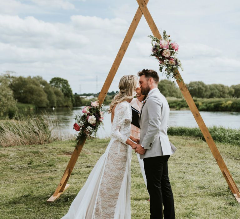 Bride in Grace Loves Lace Wedding Dress Kissing the Groom at The Altar