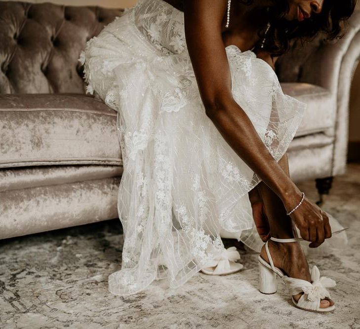 Nigerian bride putting on her wedding shoes with bows