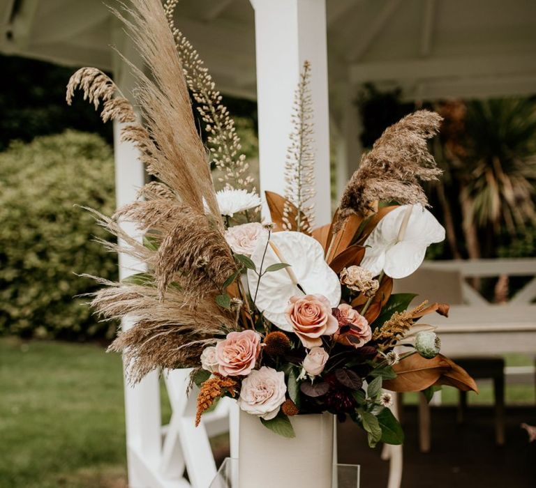 Altar floral arrangement with pampas grass, pink roses and white Anthurium flowers