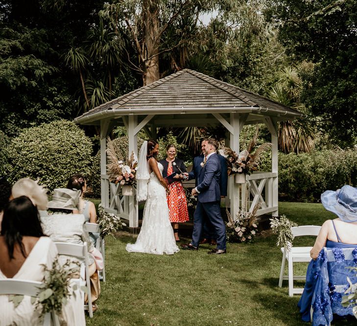 Nigerian bride and groom exchanging vows at the wooden gazebo altar