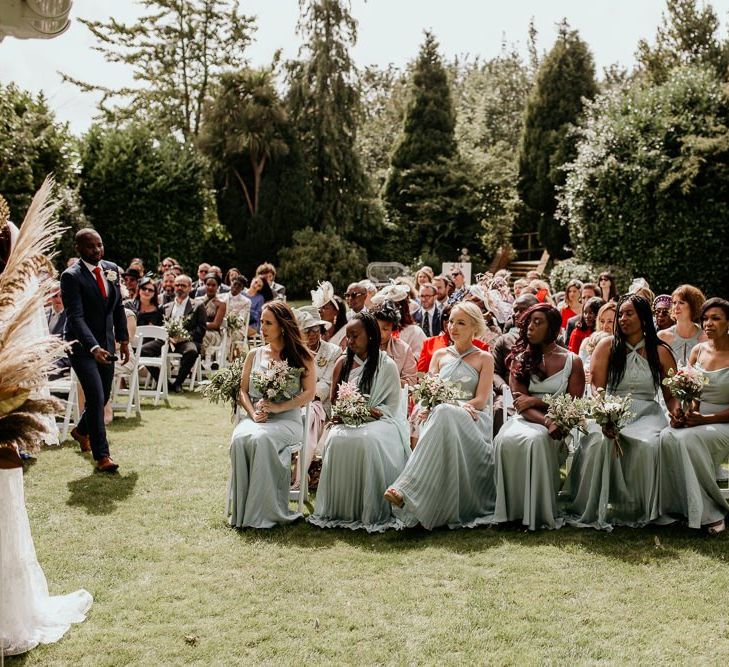 Bridal party sitting on the front row at the outdoor wedding ceremony