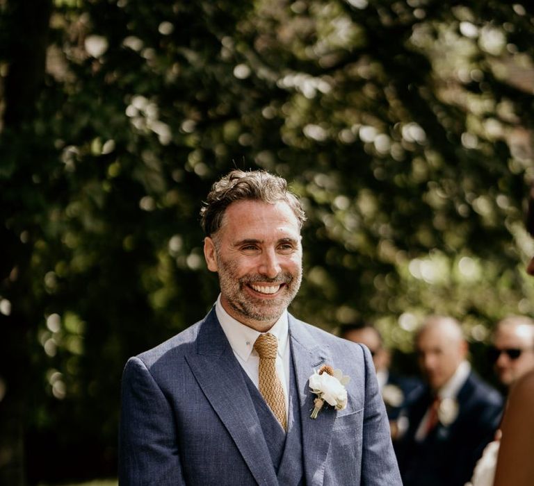 Smiling groom in navy suit standing at the altar