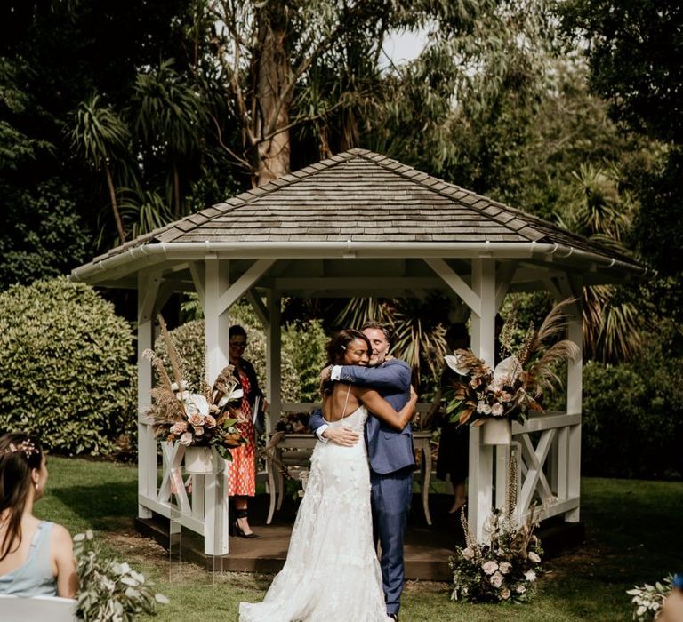 Nigerian bride and Irish Groom hugging at the outdoor wedding ceremony