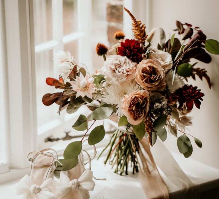 Muted flower wedding bouquet and bridal shoes with bows