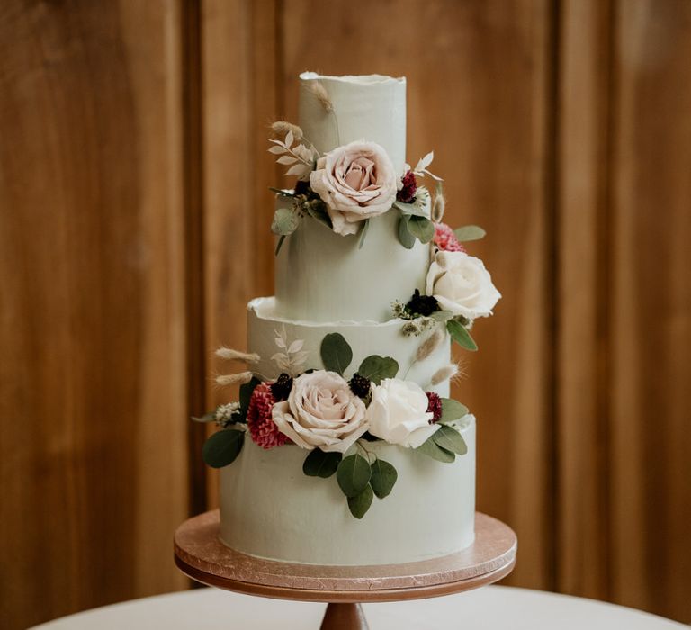 Four tier green wedding cake decorated with pink wedding flowers